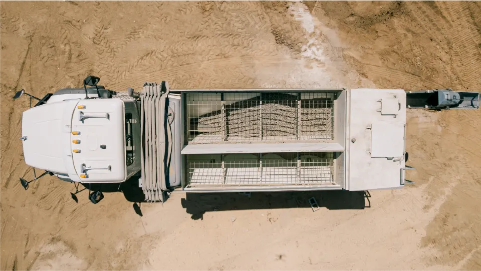 Overhead view of the Blend E050 truck parked on a dirt lot, showing the mesh covered bins on top of the mixer body