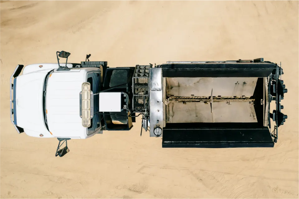 Straight down aerial view of the white truck and pothole patcher body, its hopper lid open to show the empty mixing chamber