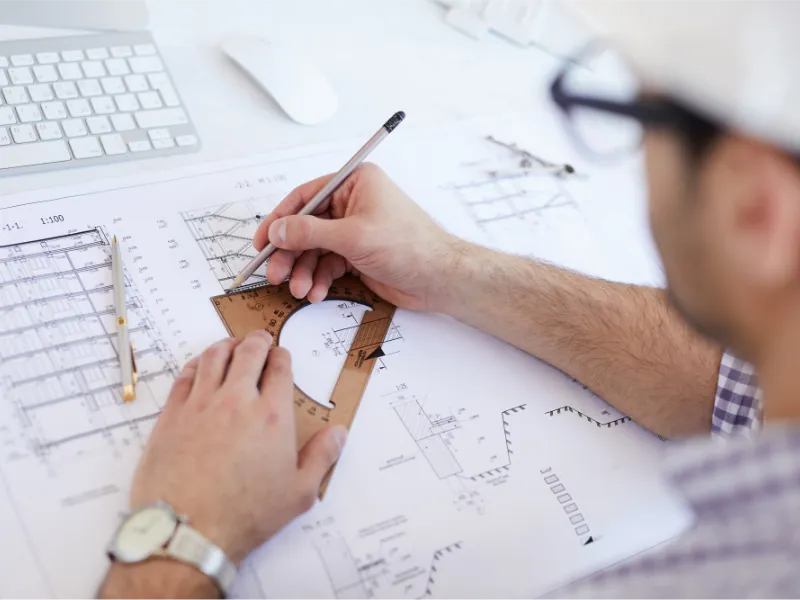 Engineer drafting technical plans with a scale ruler