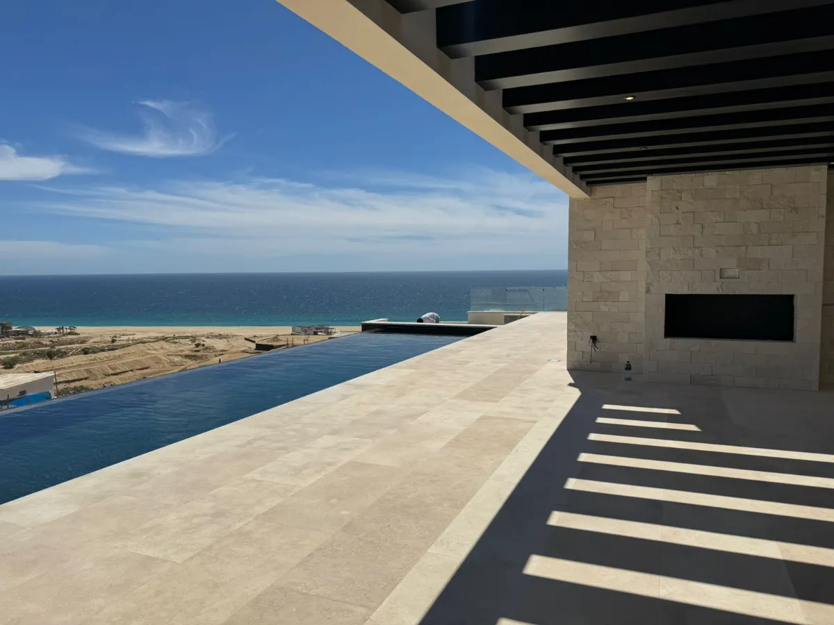 Covered stone terrace beside an infinity pool that looks out over the ocean